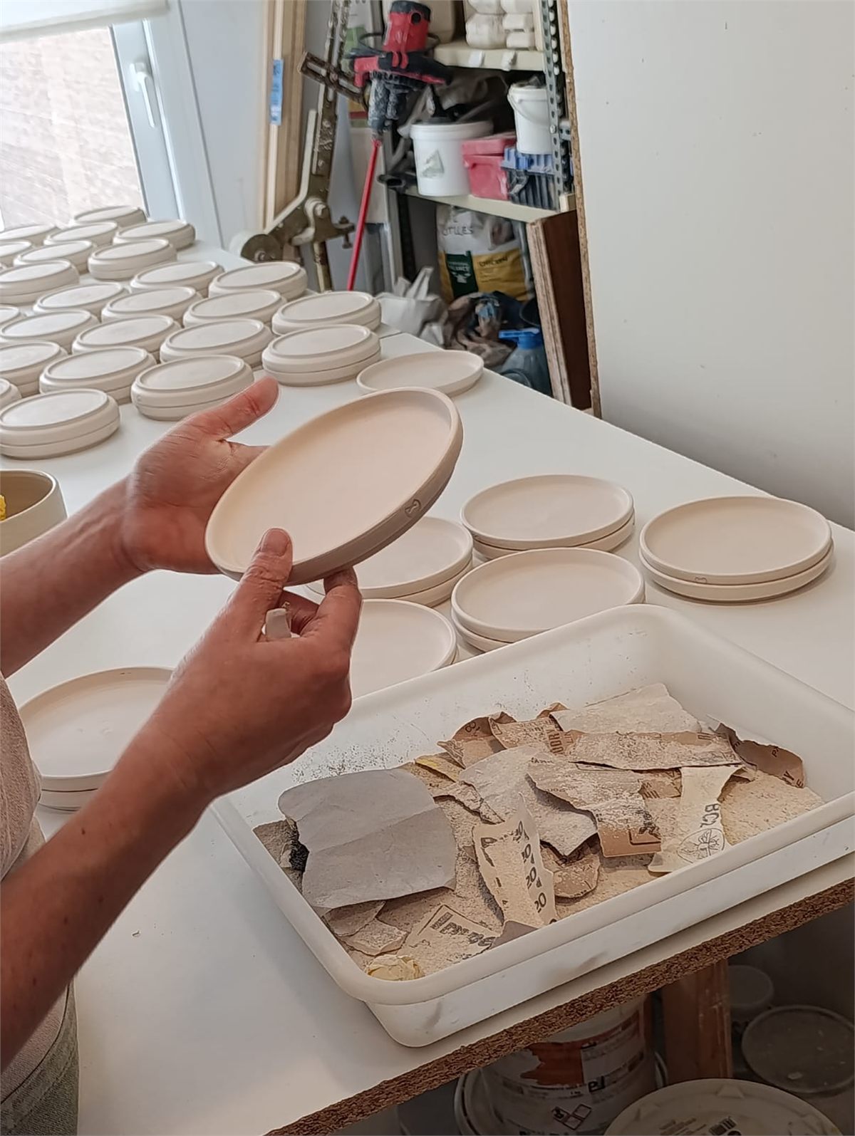 Mans sostenint un plat de ceràmica en un taller